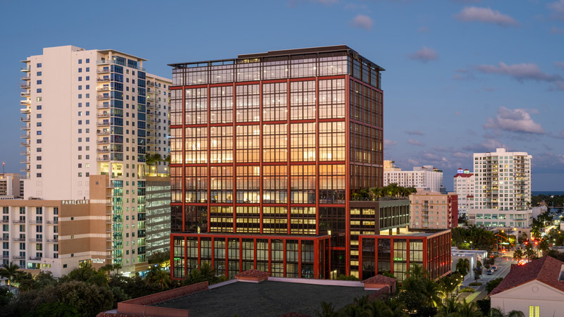 A tall commercial building in the skyline at twilight.