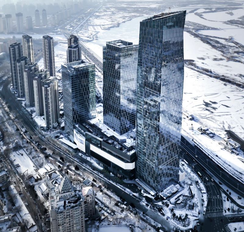 High rise towers in a city skyline during winter. Snow is in the background. 